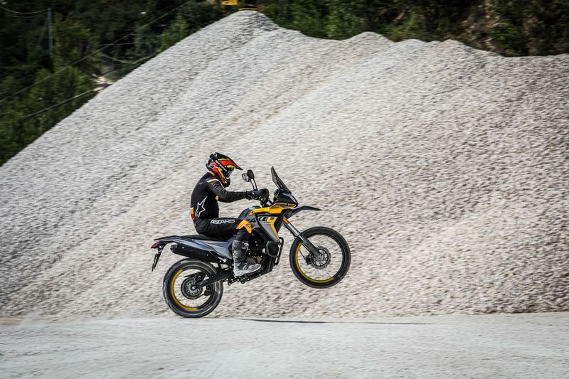 asmuo, važiuojantis motociklu žvyrkeliu